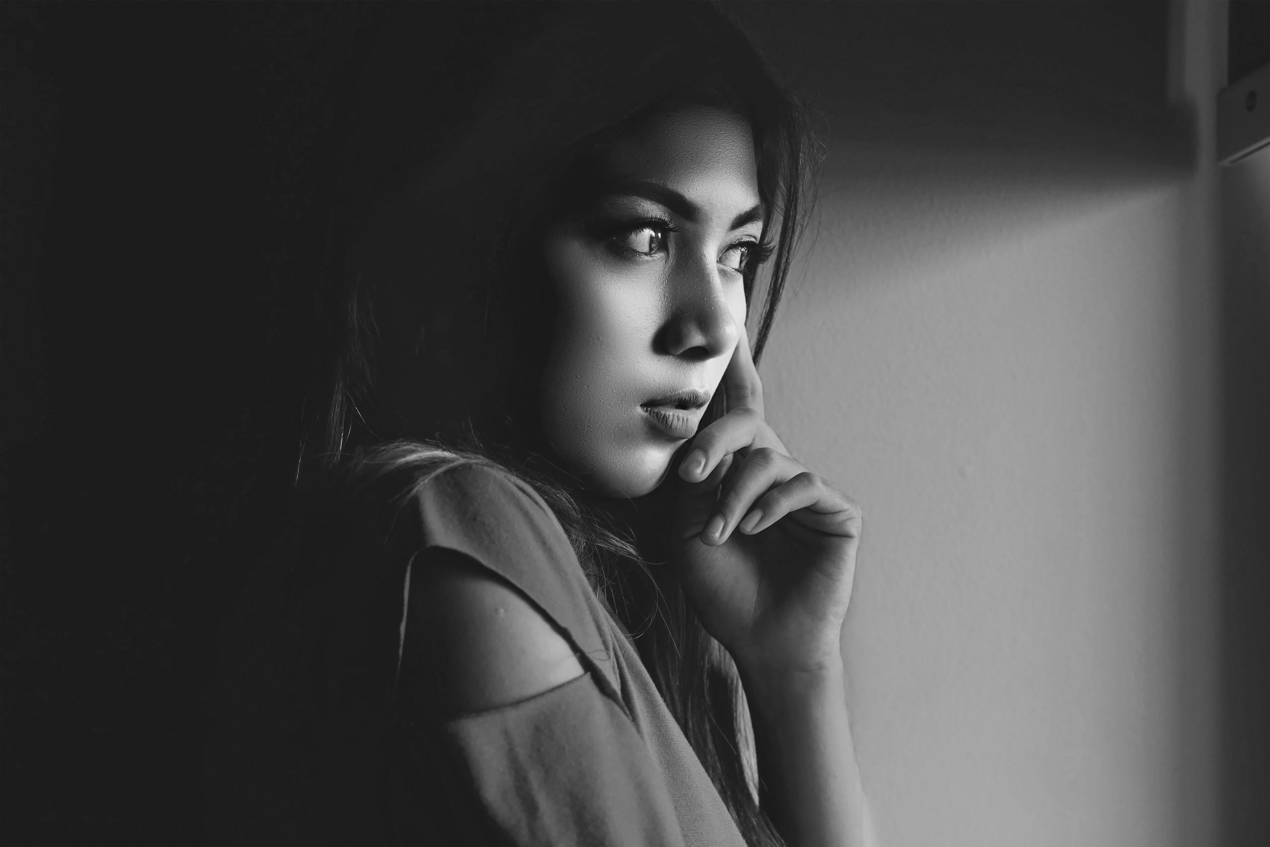 A thoughtful woman gazes out, captured in a dramatic black and white portrait.